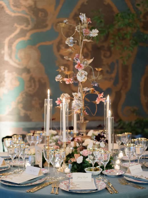 A blue and gold table with candles and porcelain flowers