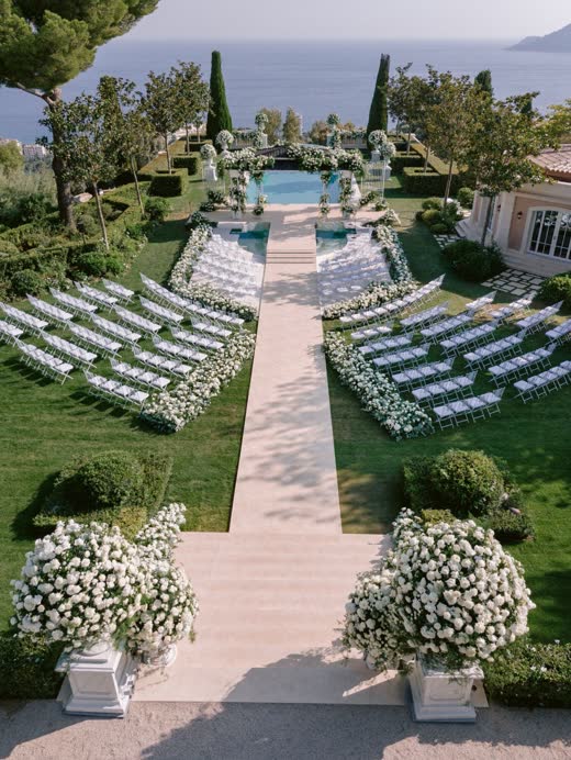 A garden ceremony with white chairs and a stone aisle, seen from above