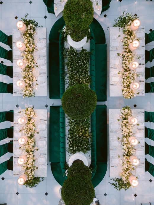 Long dinner tables around green hedges, seen from above