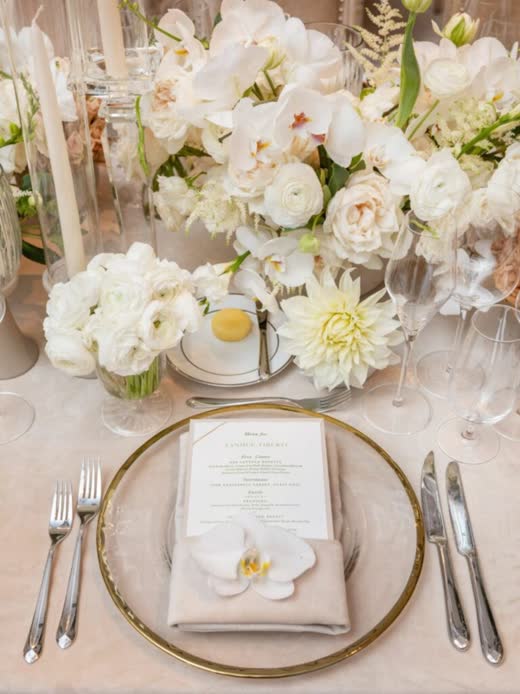 A place setting with a gold-rimmed charger and white flowers