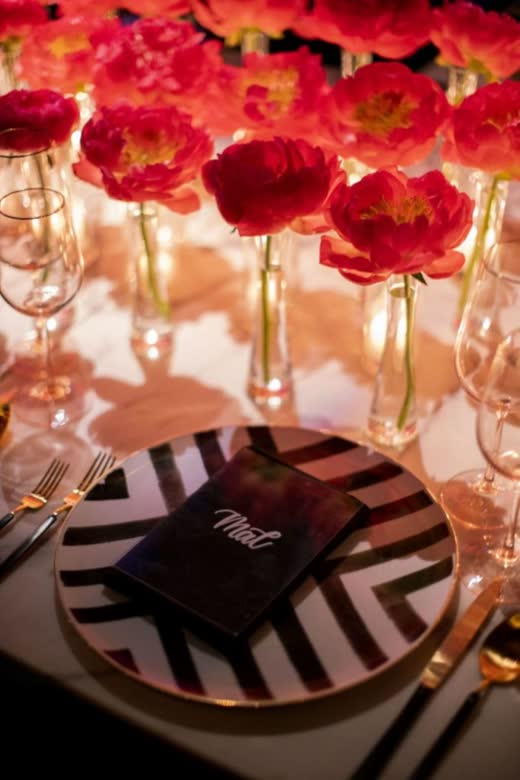Red flowers in glass over a black and white striped plate