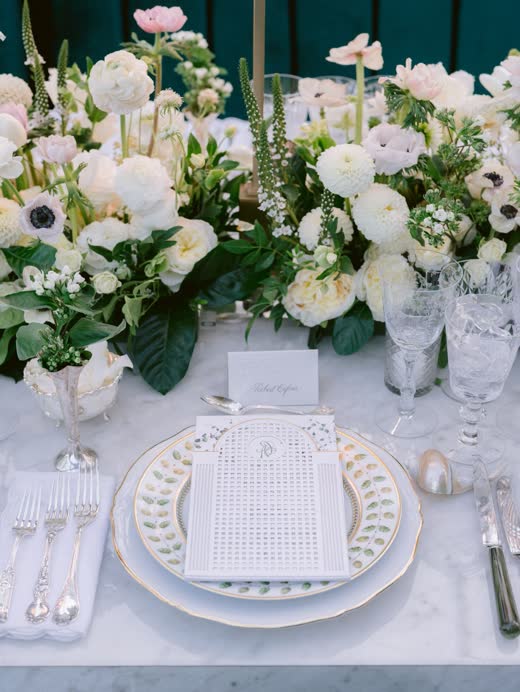 A white table setting with anemones and ranunculus